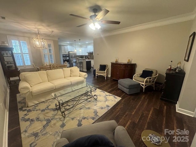 living area featuring ornamental molding, dark wood finished floors, baseboards, a ceiling fan, and a chandelier