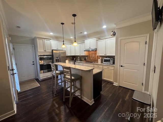 kitchen with stainless steel appliances, ornamental molding, dark wood finished floors, recessed lighting, and a kitchen island