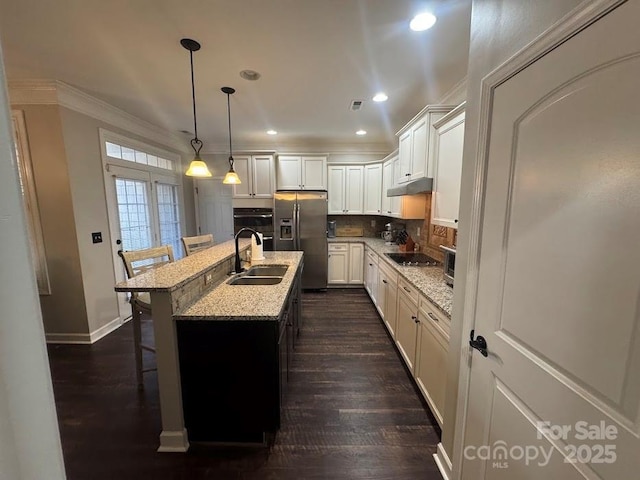 kitchen with black appliances, a sink, under cabinet range hood, recessed lighting, and a breakfast bar