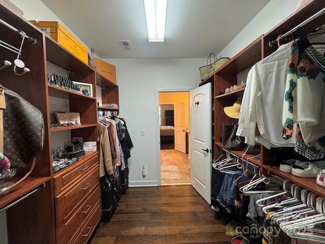 walk in closet with dark wood-style floors