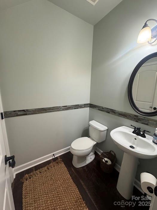 bathroom featuring wood finished floors, toilet, and a sink
