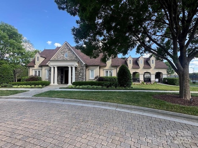 view of front of property with stone siding, stucco siding, and a front yard