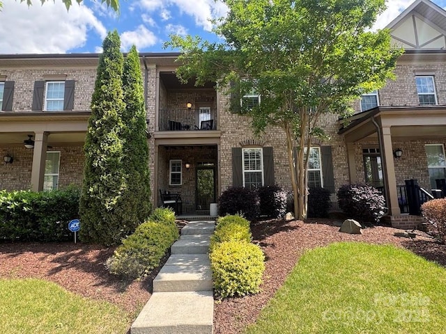 view of front of house featuring brick siding and a balcony