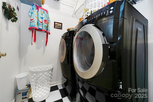 clothes washing area with washing machine and dryer, tile patterned floors, and baseboards