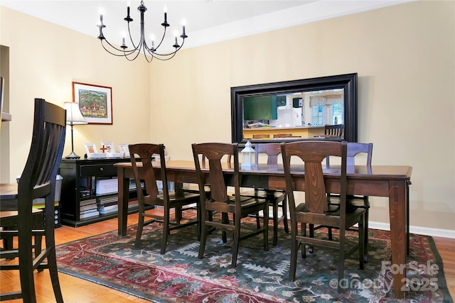 dining area with wood finished floors, a chandelier, crown molding, and baseboards