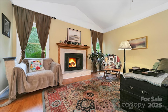 sitting room featuring vaulted ceiling, wood finished floors, a fireplace, and baseboards