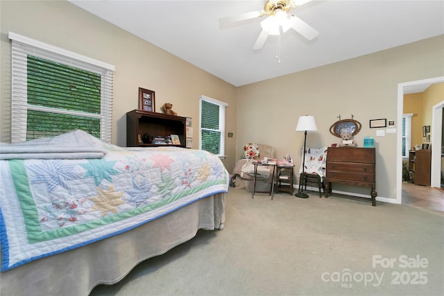 carpeted bedroom featuring a ceiling fan, multiple windows, and baseboards