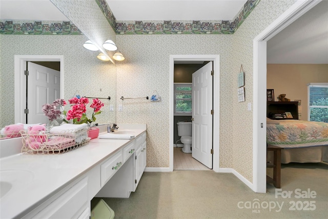 full bath with wallpapered walls, ensuite bath, baseboards, double vanity, and toilet