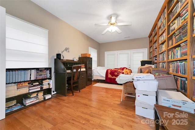bedroom featuring wood finished floors, a closet, a desk, and ceiling fan