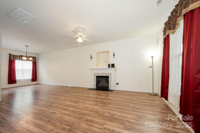 10016 Lawing School Rd, Charlotte, NC 28214 - unfurnished living room with ceiling fan, light wood finished floors, a tiled fireplace, and a chandelier