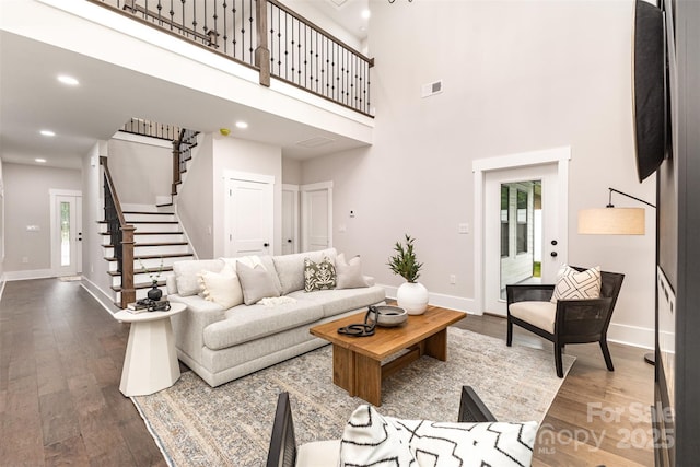 9527 Walkers Ferry Rd, Charlotte, NC 28214 - living room featuring stairway, dark wood-style floors, a towering ceiling, recessed lighting, and healthy amount of natural light