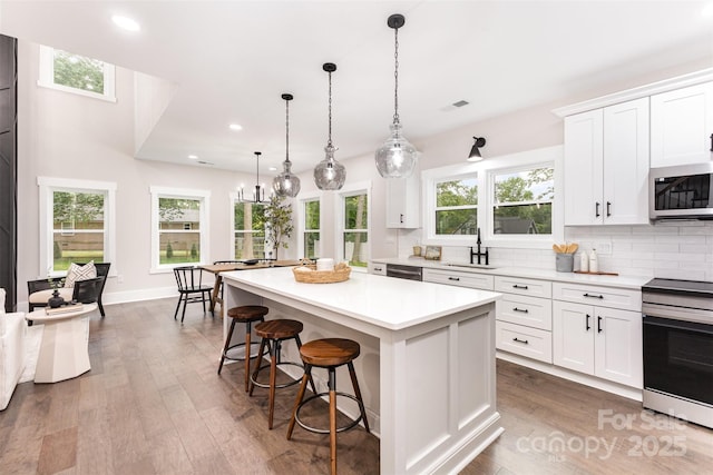 9527 Walkers Ferry Rd, Charlotte, NC 28214 - kitchen with stainless steel appliances, light countertops, decorative backsplash, a center island, and a kitchen breakfast bar