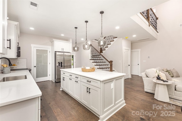 9527 Walkers Ferry Rd, Charlotte, NC 28214 - kitchen featuring stainless steel fridge, light countertops, white cabinetry, dark wood-style floors, and decorative backsplash