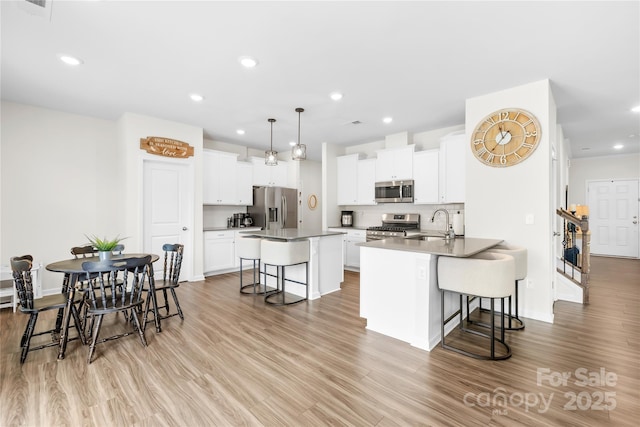 191 Tackle Box Dr, Troutman, NC 28166 - kitchen with appliances with stainless steel finishes, a kitchen breakfast bar, a sink, light wood-type flooring, and recessed lighting