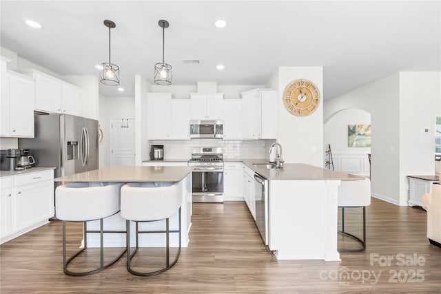 191 Tackle Box Dr, Troutman, NC 28166 - kitchen featuring appliances with stainless steel finishes, a kitchen bar, a sink, backsplash, and white cabinetry