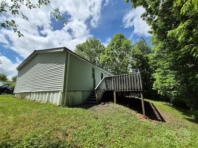 view of property exterior featuring a lawn, stairway, and a wooden deck