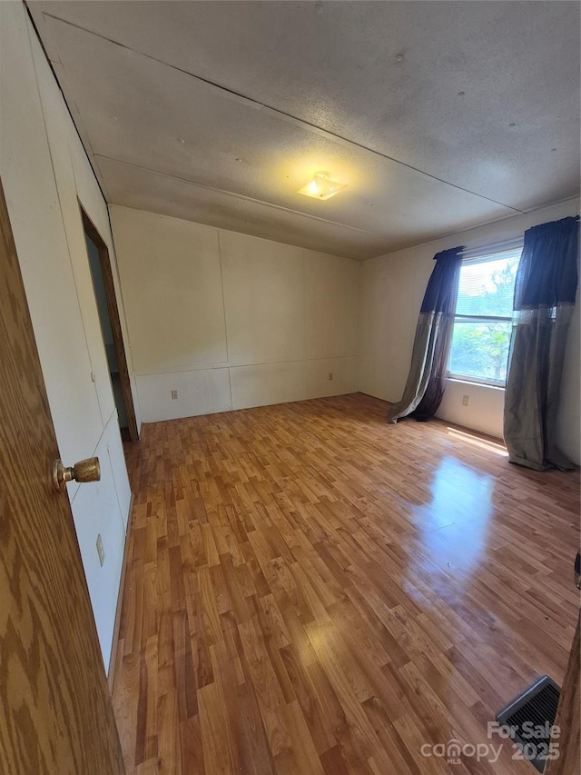 unfurnished room with a textured ceiling and light wood-style floors