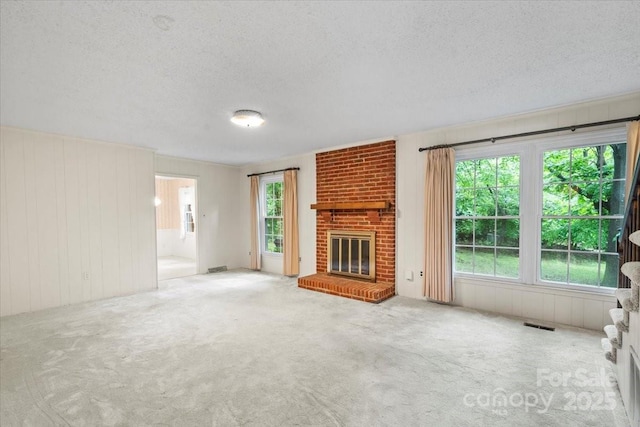 8017 Prince George Rd, Charlotte, NC 28210 - unfurnished living room with a textured ceiling, plenty of natural light, carpet flooring, a brick fireplace, and wood walls