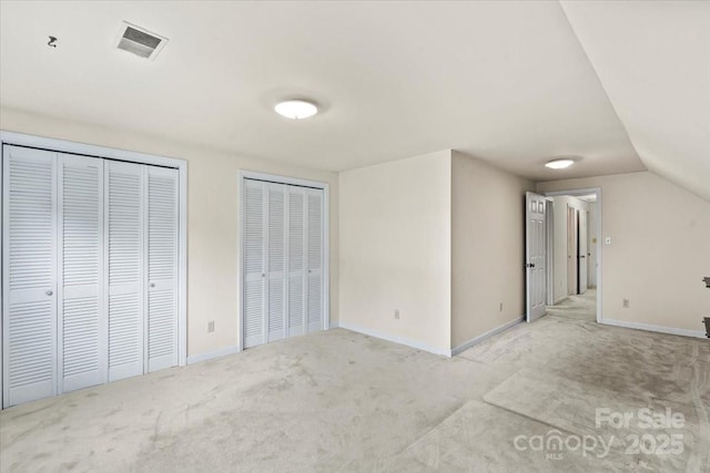 8017 Prince George Rd, Charlotte, NC 28210 - unfurnished bedroom featuring two closets, light carpet, baseboards, and vaulted ceiling