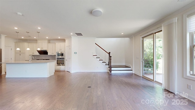 14506 Knowledge Cir, Charlotte, NC 28277 - unfurnished living room featuring stairway, wood finished floors, baseboards, recessed lighting, and a sink
