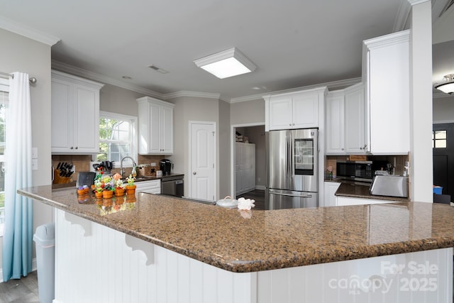 126 Strand Rd, New London, NC 28127 - kitchen featuring stainless steel appliances, a peninsula, backsplash, crown molding, and white cabinets