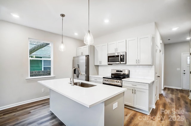 kitchen featuring dark wood finished floors, a center island with sink, stainless steel appliances, and a sink