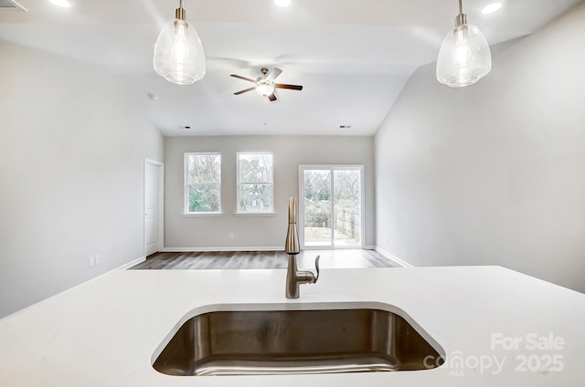 kitchen with hanging light fixtures, a ceiling fan, a sink, open floor plan, and light countertops