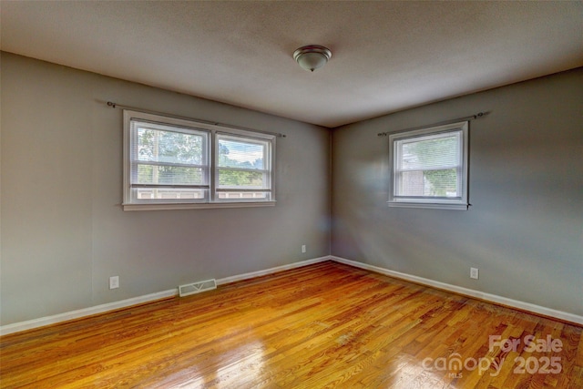 empty room with baseboards, visible vents, and light wood-style floors