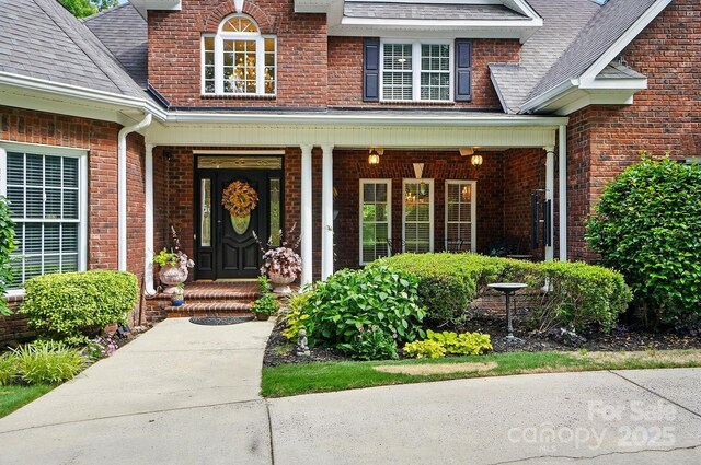 5718 Bardsey Ct, Matthews, NC 28104 - view of exterior entry with brick siding, a porch, and a shingled roof