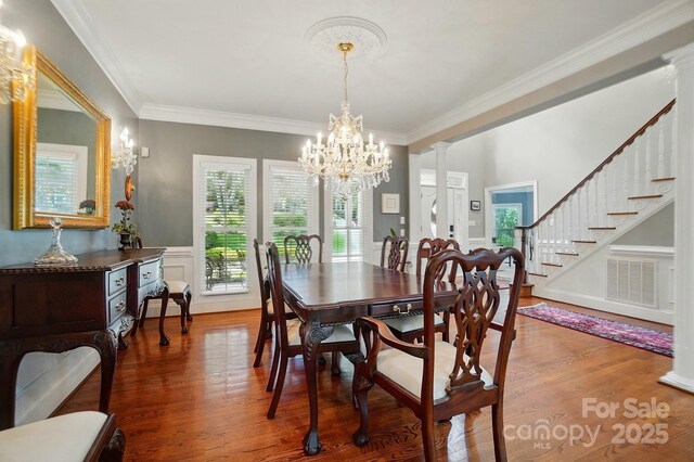 5718 Bardsey Ct, Matthews, NC 28104 - dining area featuring a chandelier, wood finished floors, ornamental molding, ornate columns, and stairs