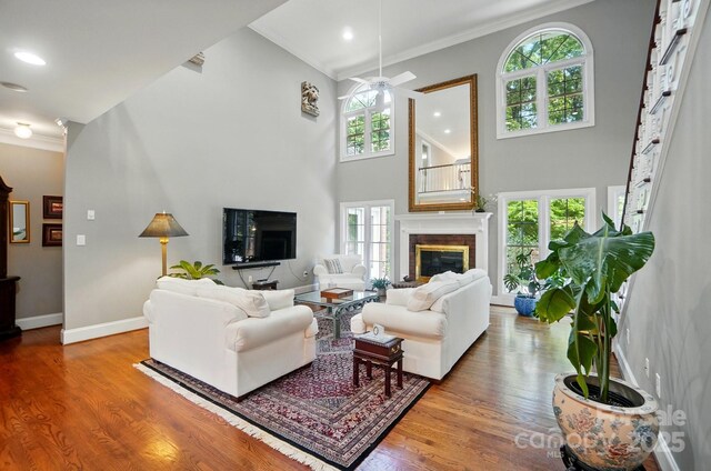 5718 Bardsey Ct, Matthews, NC 28104 - living room featuring a glass covered fireplace, ornamental molding, plenty of natural light, wood finished floors, and ceiling fan