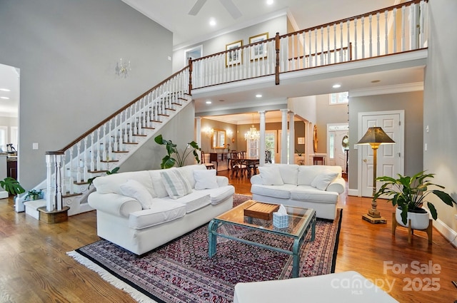 5718 Bardsey Ct, Matthews, NC 28104 - living room with a towering ceiling, wood finished floors, decorative columns, ornamental molding, and stairs