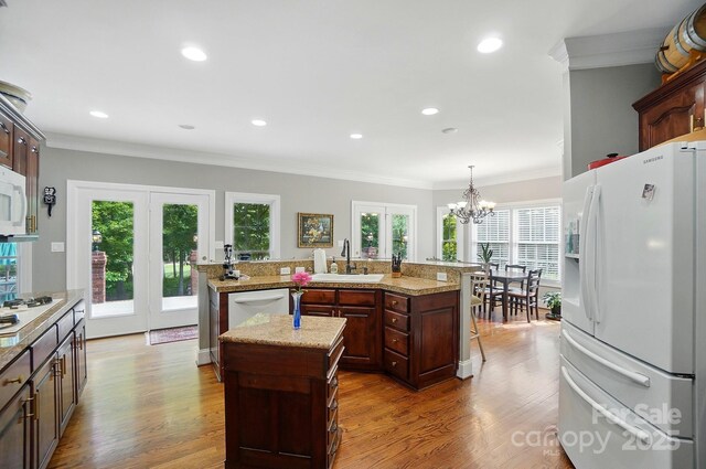5718 Bardsey Ct, Matthews, NC 28104 - kitchen featuring white appliances, an island with sink, a sink, wood finished floors, and recessed lighting