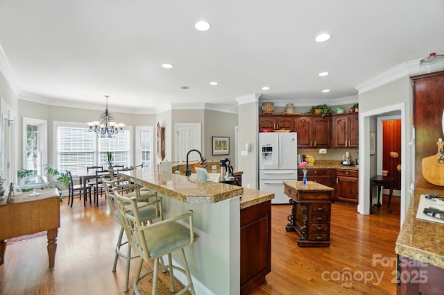 5718 Bardsey Ct, Matthews, NC 28104 - kitchen with white appliances, a kitchen island with sink, light countertops, wood finished floors, and a sink