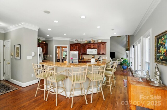 5718 Bardsey Ct, Matthews, NC 28104 - kitchen featuring white appliances, dark wood finished floors, recessed lighting, a kitchen bar, and ornamental molding