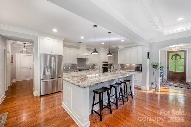 1010 Nutall Oak Ln, Belmont, NC 28012 - kitchen with stainless steel appliances, tasteful backsplash, a kitchen island with sink, a kitchen bar, and custom range hood
