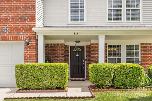 view of exterior entry with brick siding and a porch