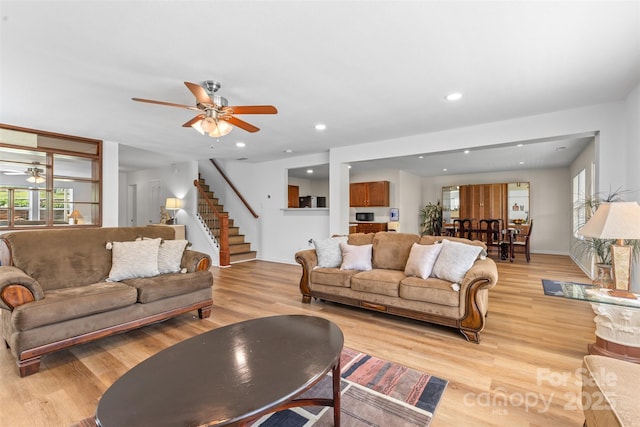 living area featuring ceiling fan, healthy amount of natural light, stairway, light wood-style flooring, and recessed lighting