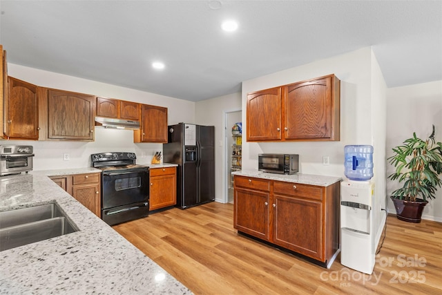 kitchen featuring black appliances, under cabinet range hood, light wood-style flooring, light stone countertops, and recessed lighting