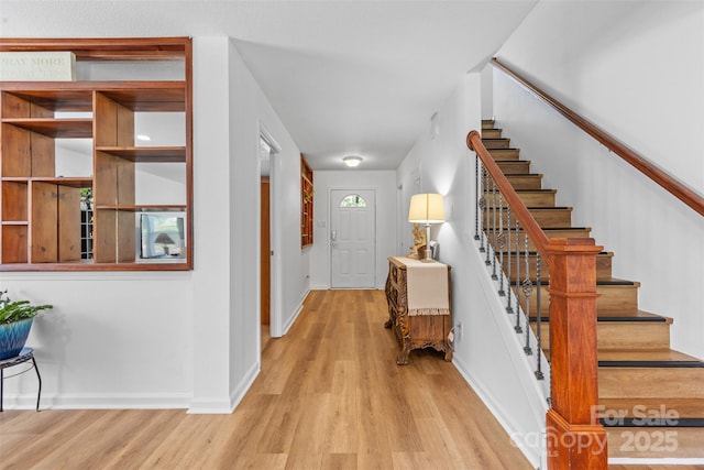 entryway with wood finished floors, baseboards, and stairway