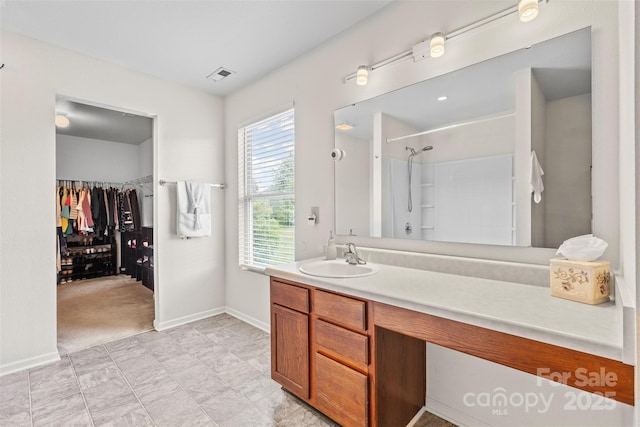 full bathroom with vanity, a spacious closet, baseboards, and a shower