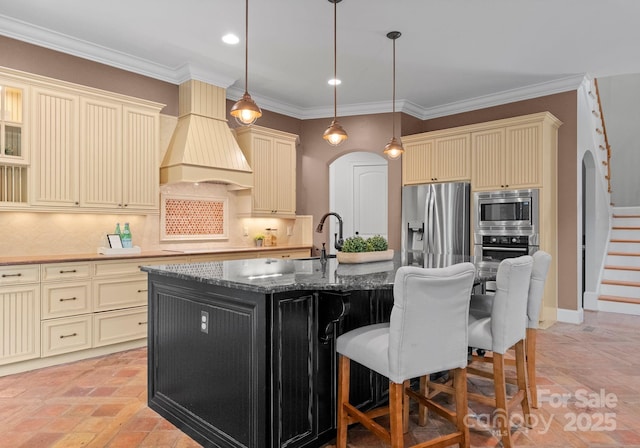 3815 Stoney Ridge Trl, Charlotte, NC 28210 - kitchen featuring cream cabinets, appliances with stainless steel finishes, premium range hood, dark stone counters, and ornamental molding