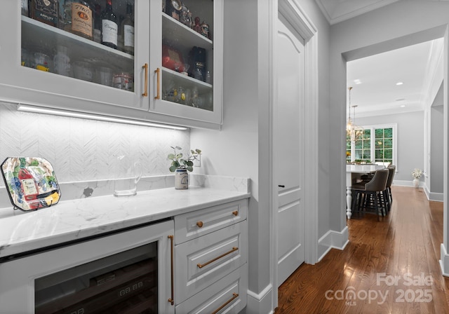 12835 Ninebark Trl, Charlotte, NC 28278 - bar featuring beverage cooler, ornamental molding, dark wood finished floors, a chandelier, and baseboards