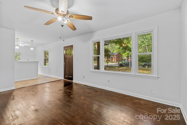 unfurnished room featuring baseboards, hardwood / wood-style floors, and ceiling fan