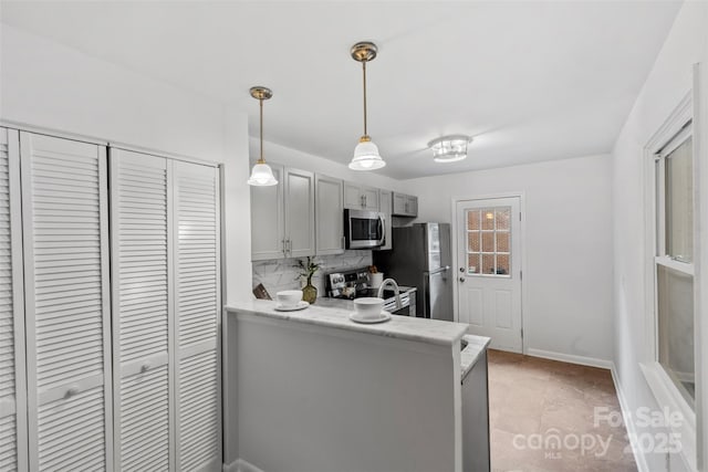 kitchen featuring stainless steel appliances, tasteful backsplash, baseboards, gray cabinetry, and hanging light fixtures