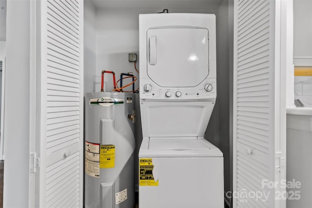 laundry room featuring water heater, stacked washer / drying machine, and laundry area