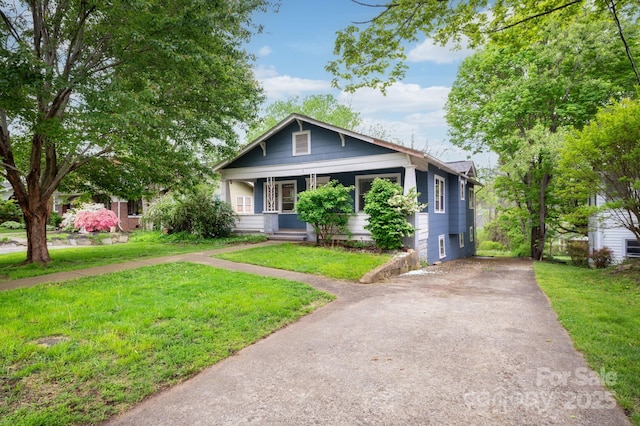 bungalow with a front lawn, driveway, and covered porch