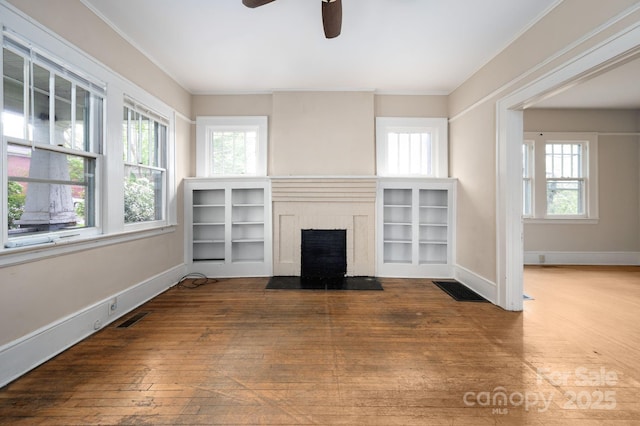 unfurnished living room with wood-type flooring, plenty of natural light, and visible vents