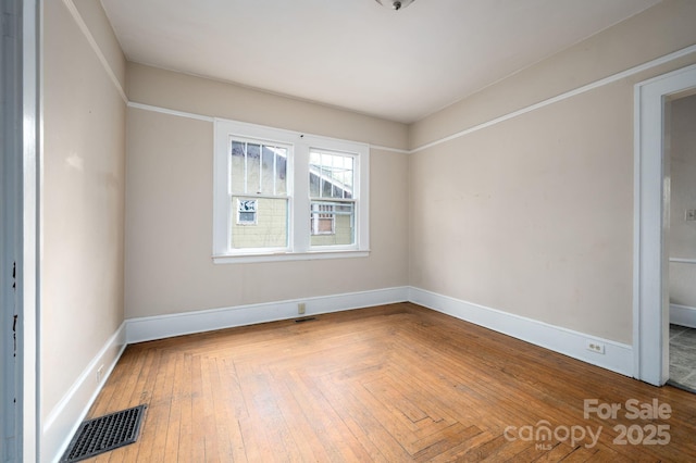 unfurnished room with baseboards and visible vents
