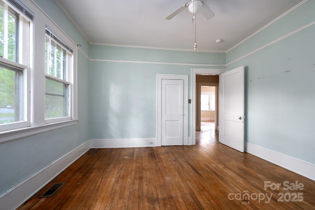 spare room with a ceiling fan, baseboards, ornamental molding, wood-type flooring, and visible vents